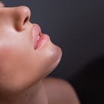 Close-up portrait highlighting the flawless skin and natural makeup of a woman's face.